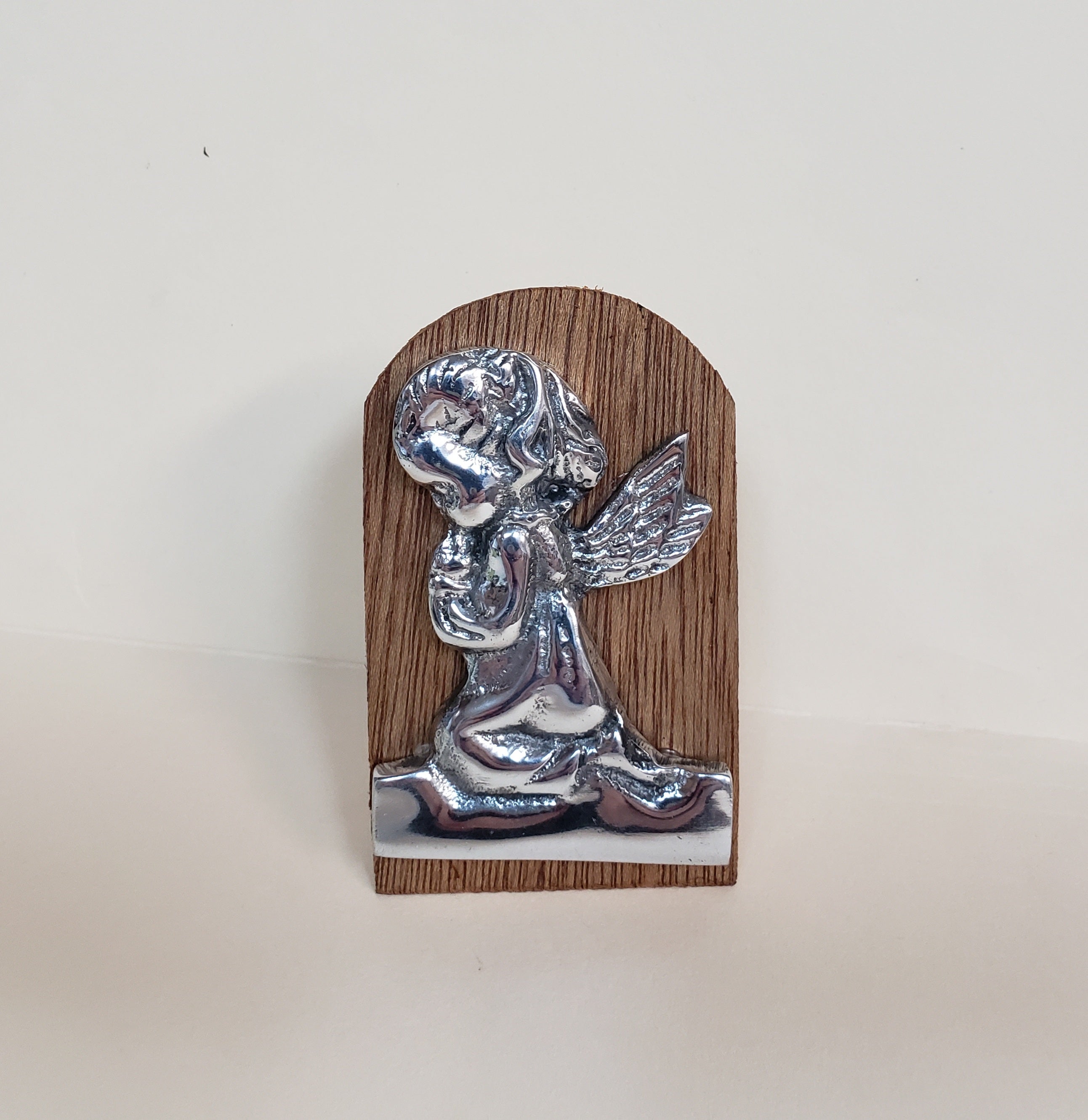 Figura de peltre de un niño rezando sobre un soporte de madera