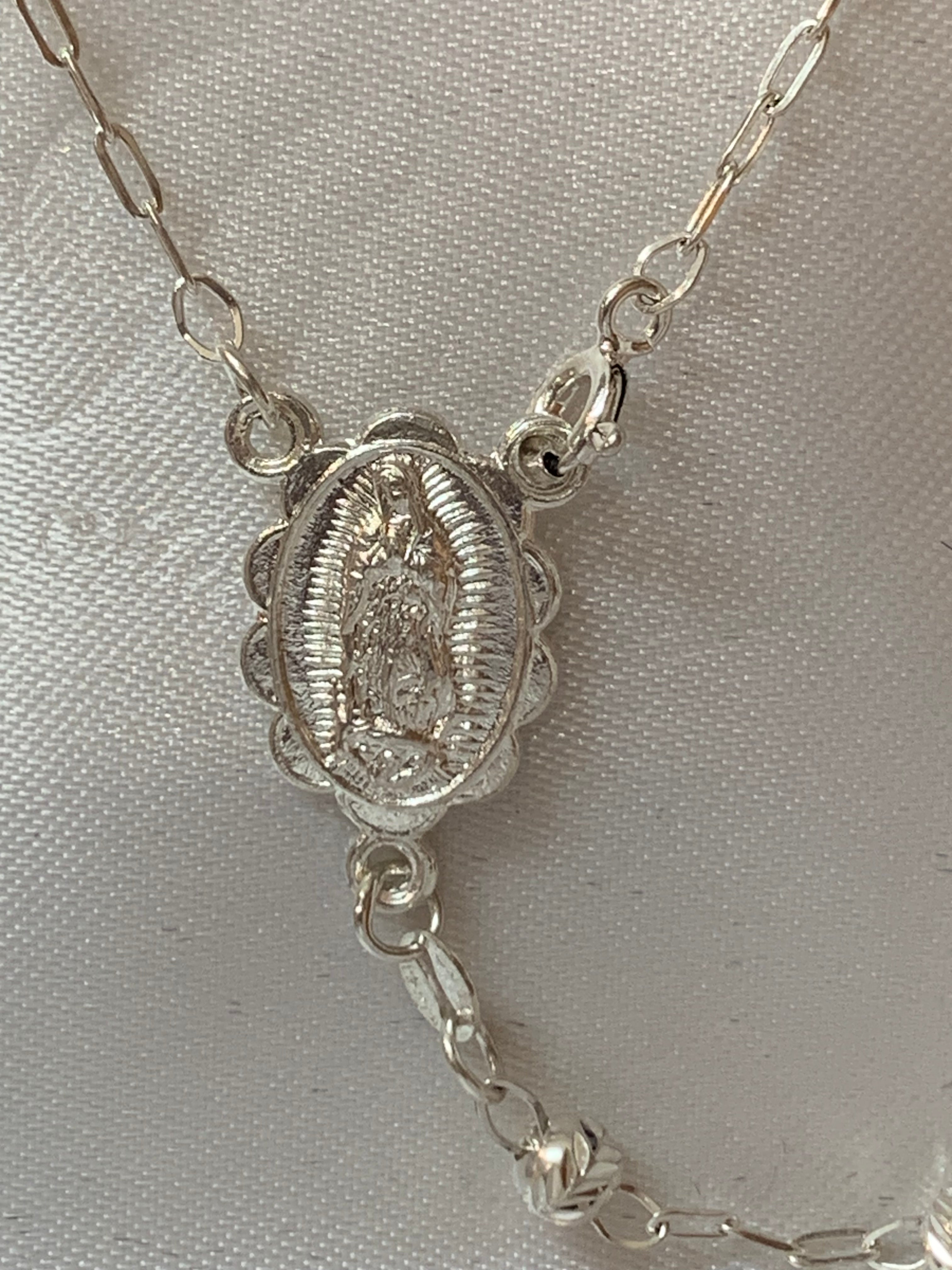 Rosario de plata con medalla de San Benito o Nuestra Señora de Guadalupe en el centro