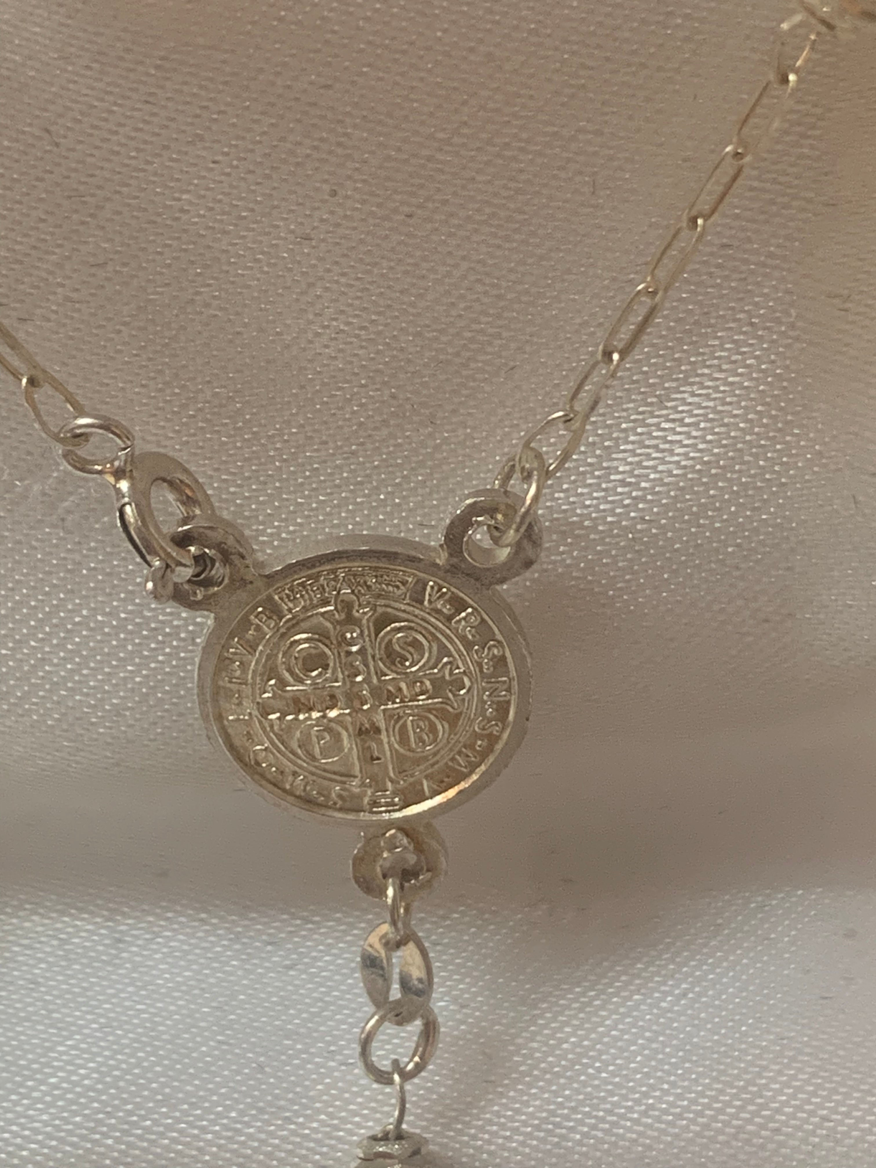 Rosario de plata con medalla de San Benito o Nuestra Señora de Guadalupe en el centro
