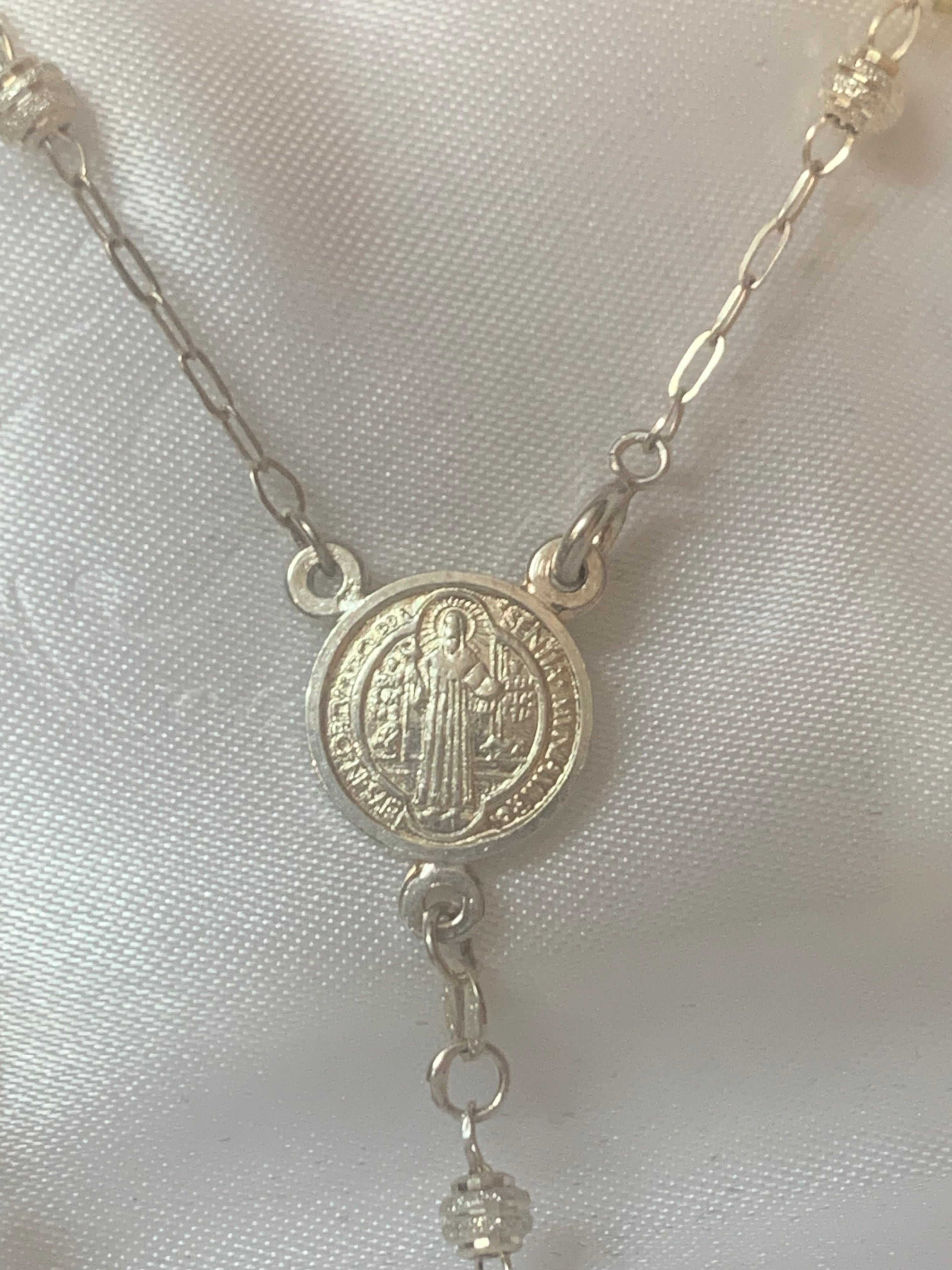 Rosario de plata con medalla de San Benito o Nuestra Señora de Guadalupe en el centro
